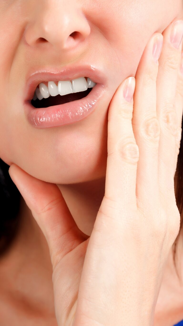 Mujer con la mano en la mandíbula por un dolor dental